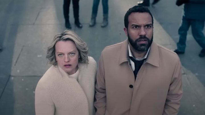 June and Luke looking up at a screen in a scene from The Handmaid's Tale season 5.