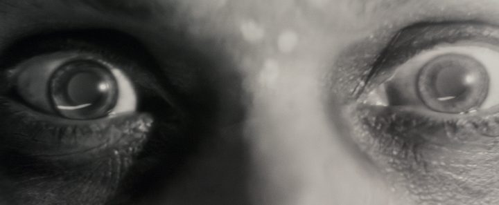 A pair of eyes stare out at the camera in a scene from Werewolf By Night.