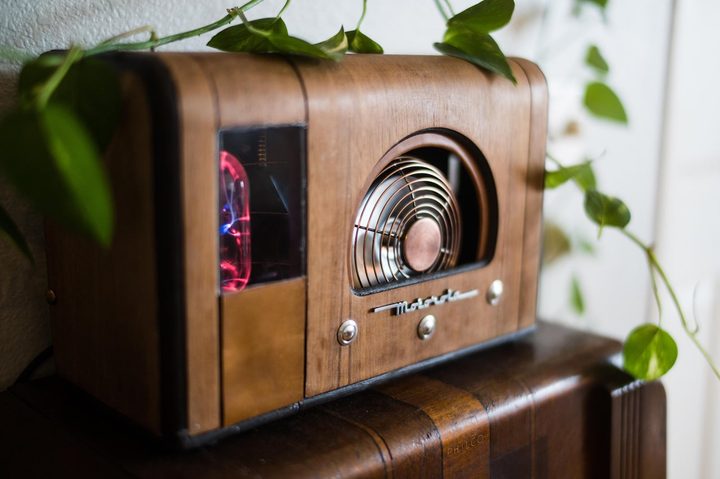 A pc inside a vintage wooden Motorola radio case with a stainless steel fan at the front, surrounded by green leaves.