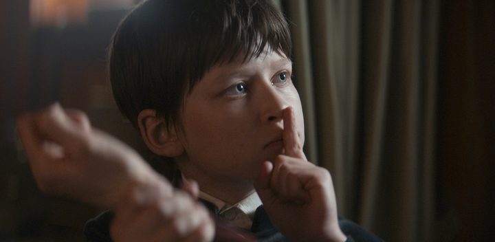 A boy puts a finger to his mouth in 1899.