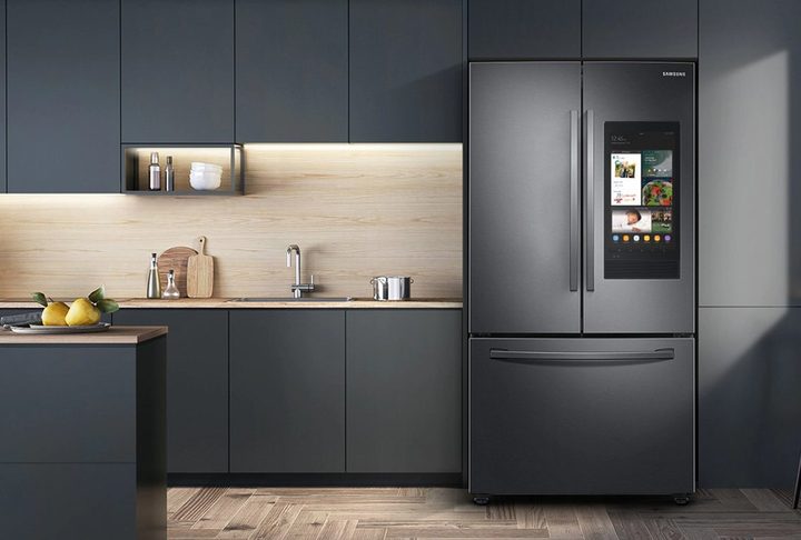28 cu. ft. Samsung 3-Door French Door Refrigerator with Family Hub in a kitchen with dark gray cabinets and a wooden floor