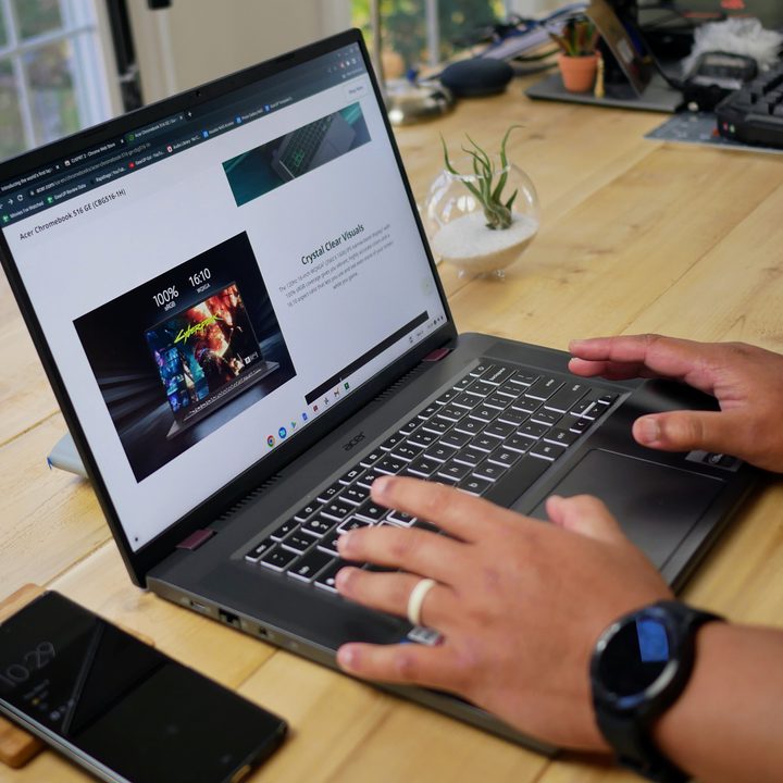 Acer 516 GE on desk with two hands typing.