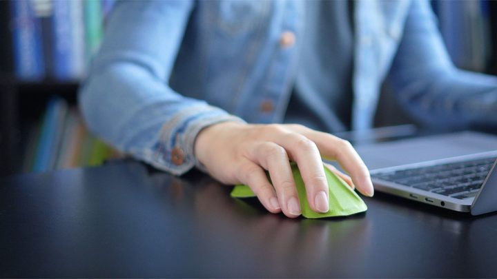 And Air.0 mouse being used be a person on a desk next to a laptop.