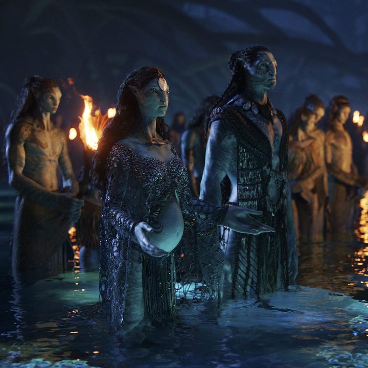 Two Na'vi characters stand in the water in a scene from Avatar: The Way of Water.