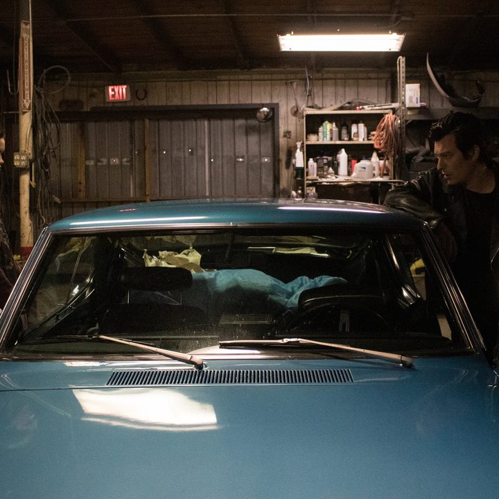 Two people stand on each side of the car in a scene from Blood Relatives.
