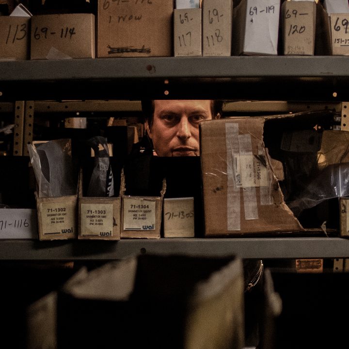 A man stares through a shelf in a scene from Blood Relatives.