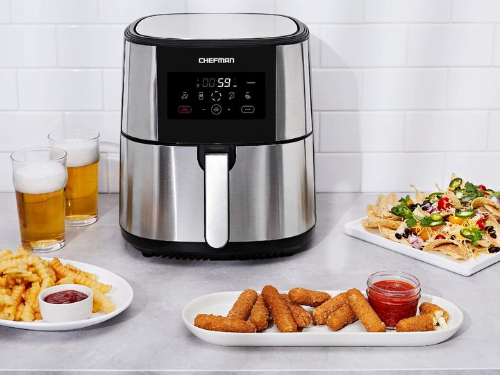 Chefman 8-Quart Turbo Fry Stainless Steel Air Fryer on a white counter with cooked dishes.