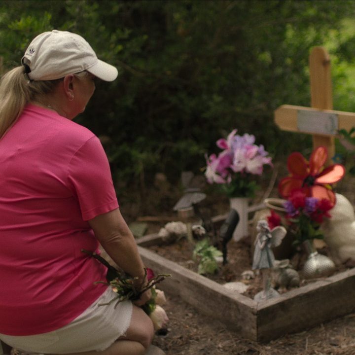 A woman kneels before a cross in Crime Scene: The Texas Killing Fields.