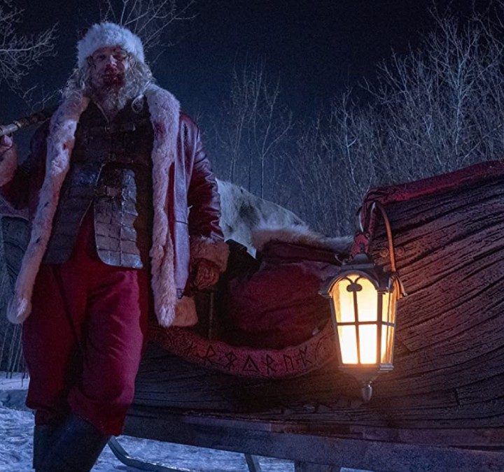 David Harbour holds a weapon in front of a sled from a scene in Violent Night.