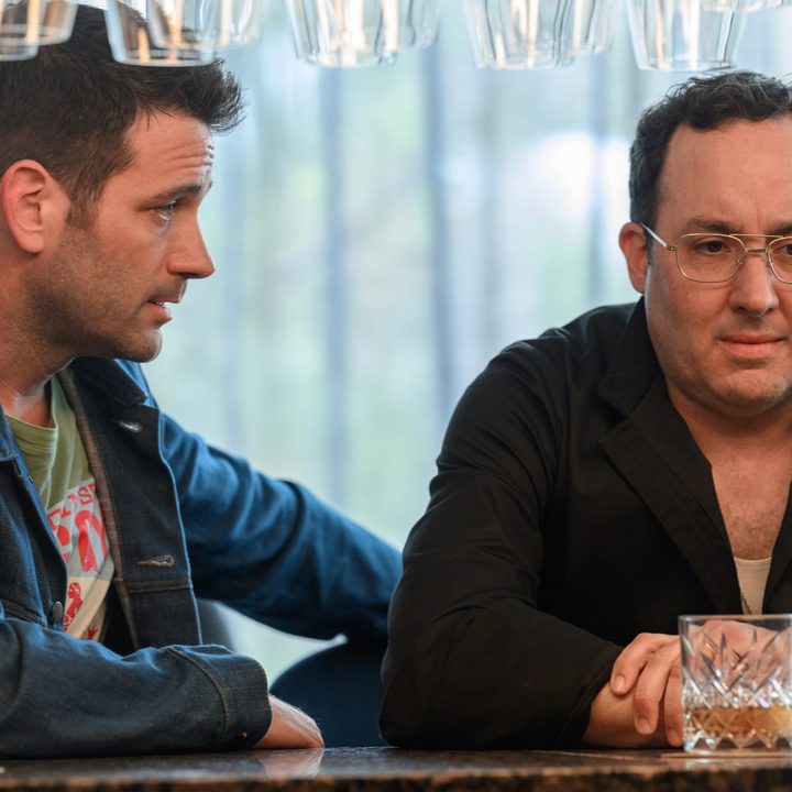 Two men sit at a bar and console each other in a scene from Irreverent.