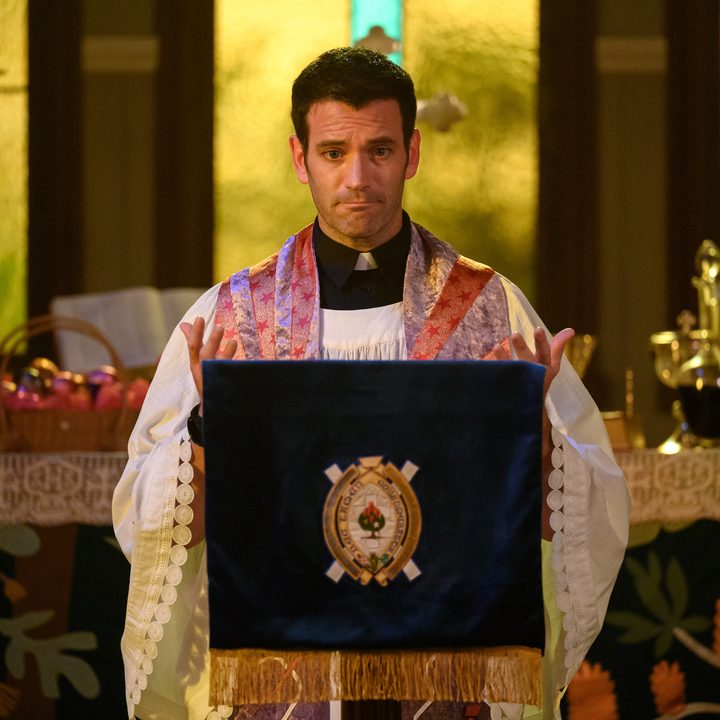 A reverend stands at the podium in a scene from Irreverent.
