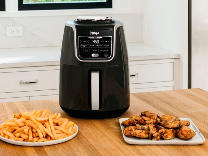 Ninja Air Fryer Max XL on a kitchen table with wings and fries.