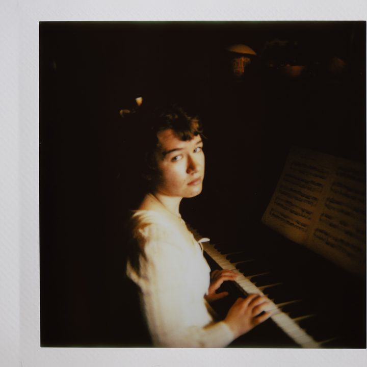 Instax photo of a woman playing the piano.