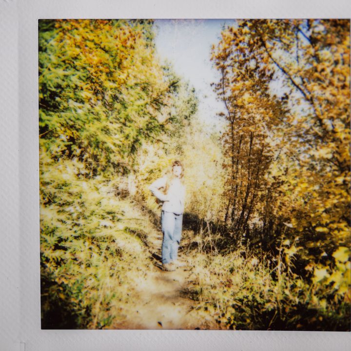 Instax photo of a hiker on a trail with autumn leaves.
