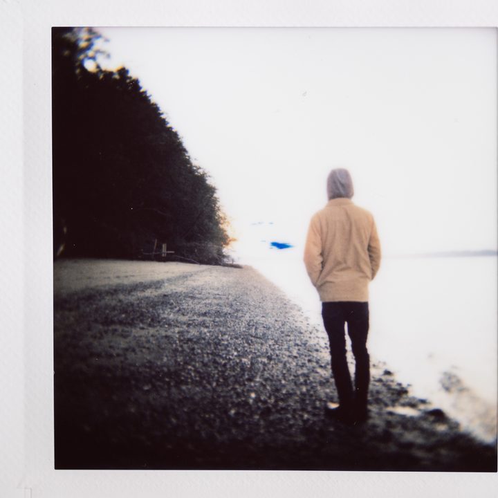 Instax photo of a man standing on a beach.