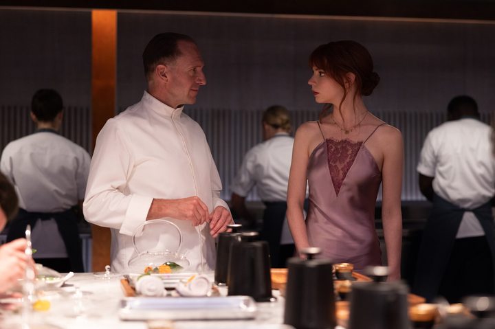 Ralph Fiennes and Anya Taylor-Joy look at each other in The Menu.