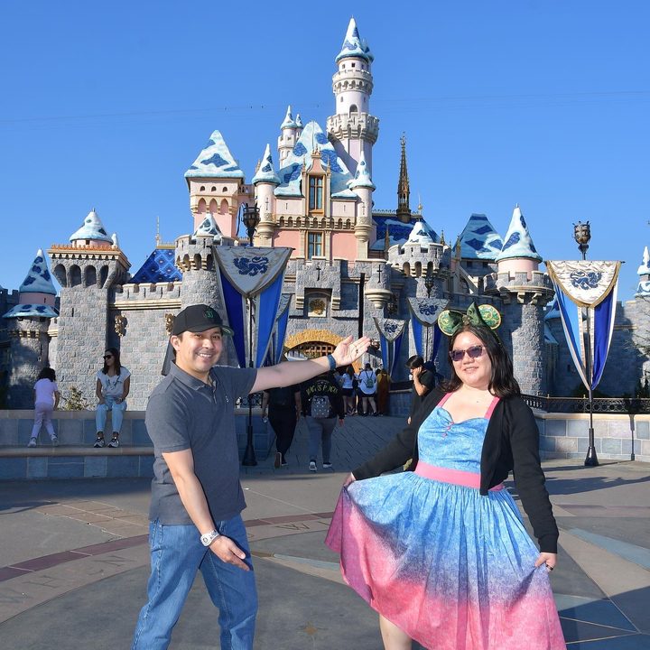 Christine and husband pose in front of Disneyland's castle.