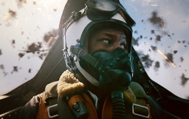 A Black pilot played by Jonathan Majors looks at missiles exploding around him in Devotion.