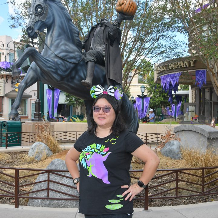 Christine poses in front of headless horseman statue at DCA with Magic Eraser used on background people.