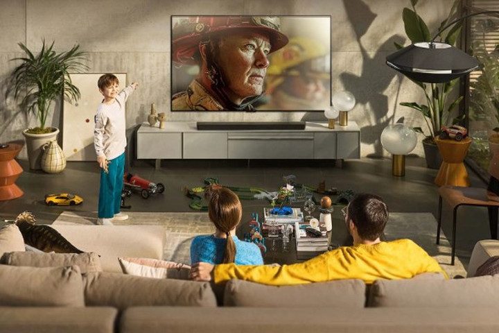 A family sit on the couch watching the LG 55-inch 4K OLED WebOS Smart TV.