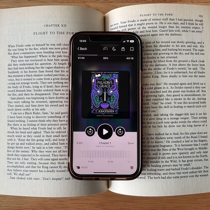 The Libby app displayed on an iPhone 12 resting on an open book.