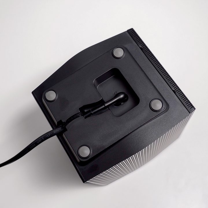 A power cord is neatly routed out the bottom of a surround speaker in the Samsung Q990B soundbar system
