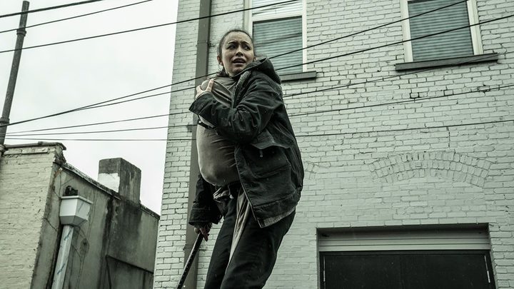 Rosita looking terrified, baby Coco strapped to her in a scene from The Walking Dead.