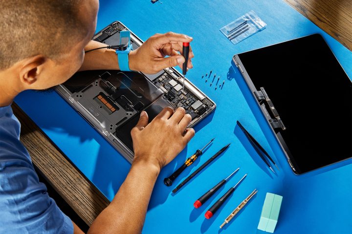 A person repairing a MacBook using Apple's self-service repair kit.