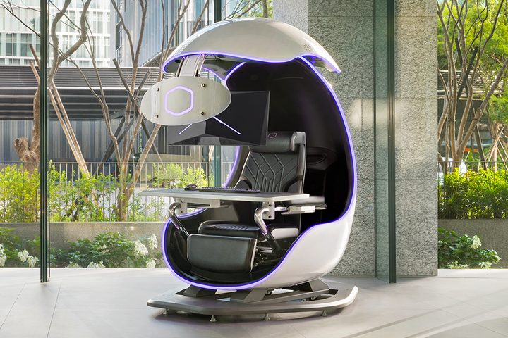 The Cooler Master Orb X gaming station next to a window with trees and buildings behind it.