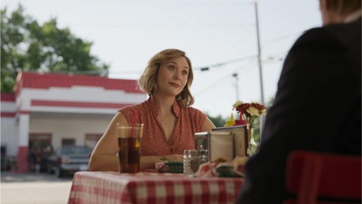 Candy Montgomery smiling while sitting at a table in Love and Death.