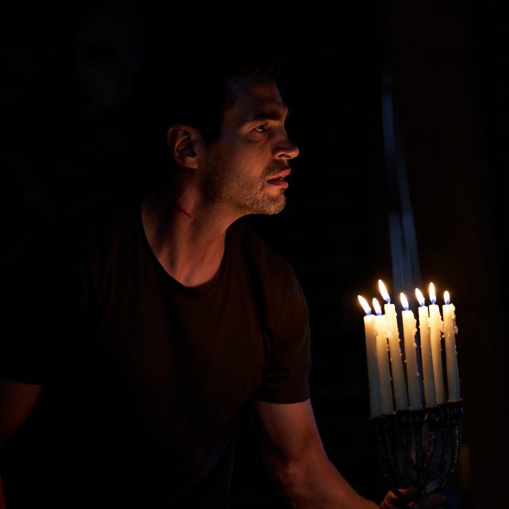 A man holds a menorah in a scene from Lullaby.