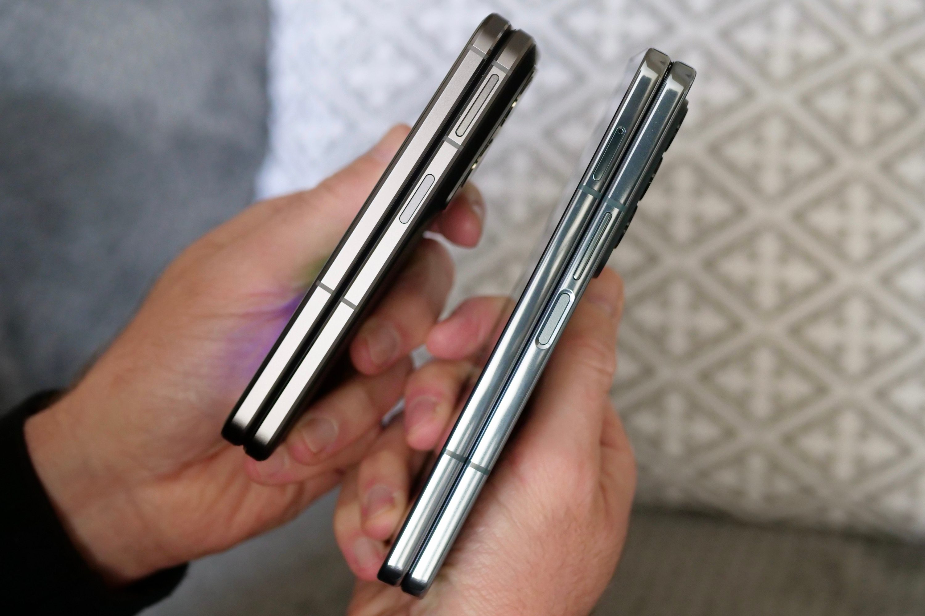 The Oppo Find N2 and Galaxy Z Fold 4 seen from the side, held in a person's hands.