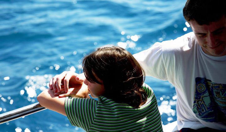 A father sits next to his child in Aftersun.