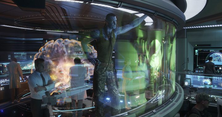 A large Na'vi stands next to a human in a control room in a scene from Avatar: The Way of Water.