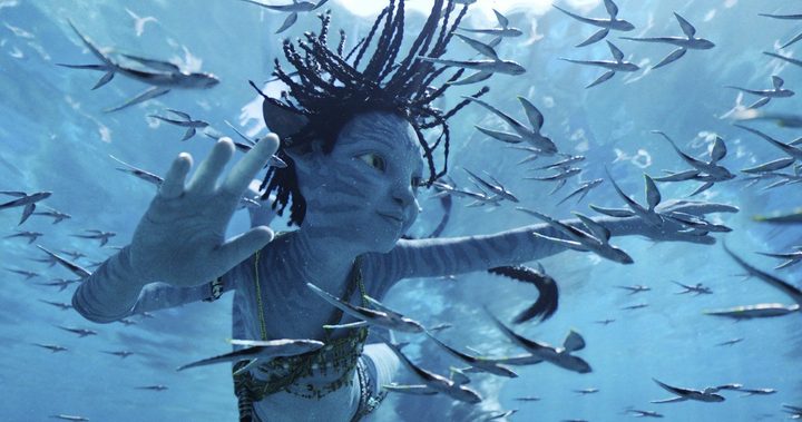 A blue-skinned Na'vi child swims underwater in a scene from Avatar: The Way of Water.