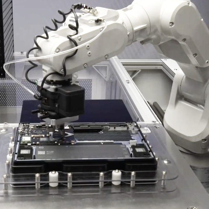 A robot arm removing a motherboard from a laptop.
