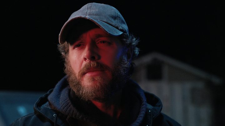 Ben with a beard and baseball hat looking upset on Manifest.