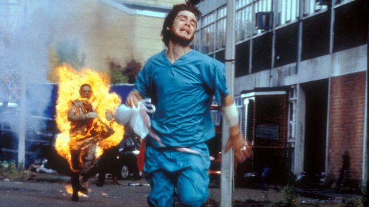 A man runs from a enflamed zombie in 28 Days Later.