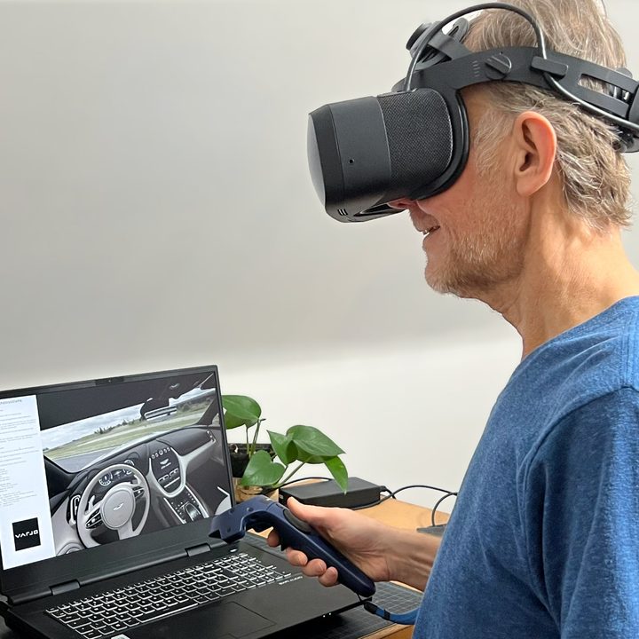 Alan Truly sits in front of a laptop, wears the Varjo Aero VR headset.
