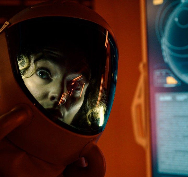 A woman looks scared in a spacesuit.