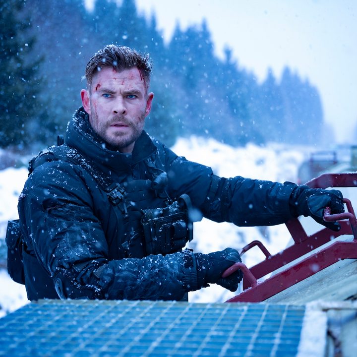Chris Hemsworth holds on to the sign of a train in Extraction 2.
