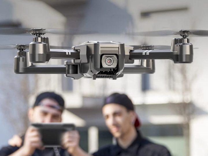 Two men behind the flying Holy Stone HS440 Drone.