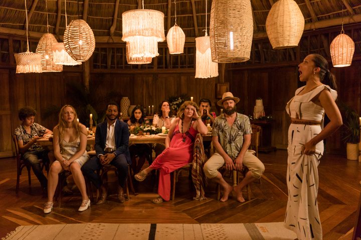 A crowd of people sit in a banquet room during a scene from The Drop.