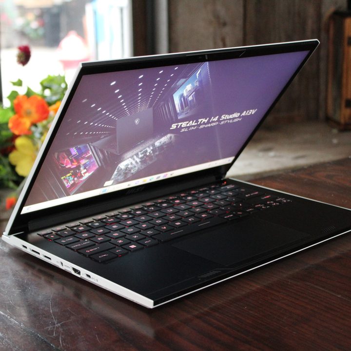 The MSI Stealth 14 Studio laptop sits on a table, with its lid half-open.
