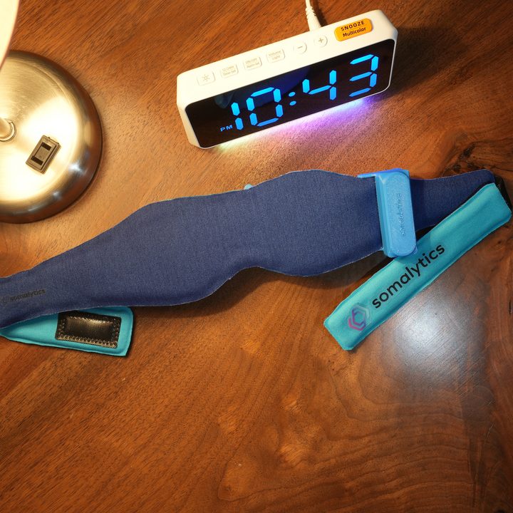 Somalytics’ SomaSleep sleep mask on a bedside table.