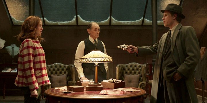 A man points a gun at 2 people in The Outfit.
