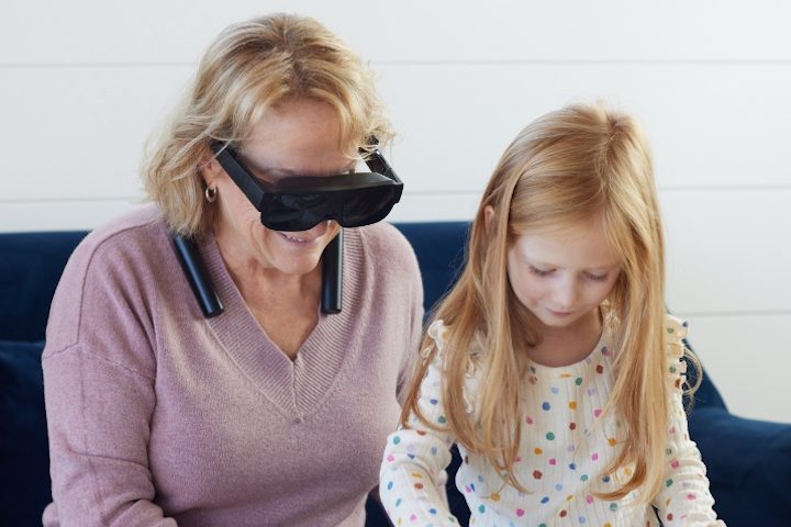 Woman wearing eSight Go, sitting with a child.