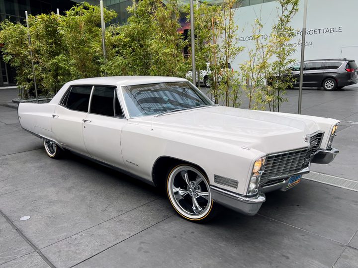 A 1976 Cadillac Fleetwood parked outside a hotel.