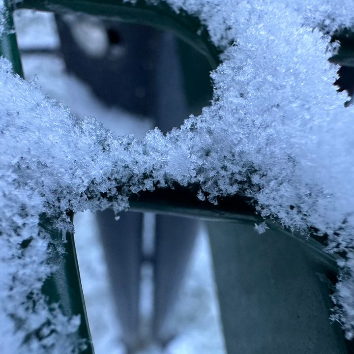 Macro photo of snow on a green picnic table.