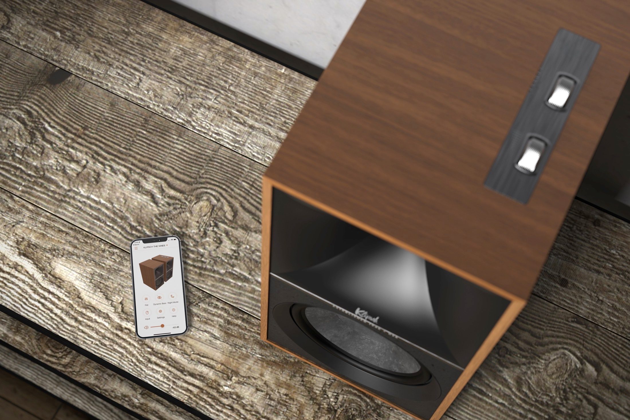 Klipsch The Nines in walnut finish seen next to a smartphone.